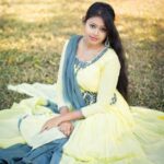 Portrait of a woman in traditional attire, sitting gracefully in a sunny park setting.